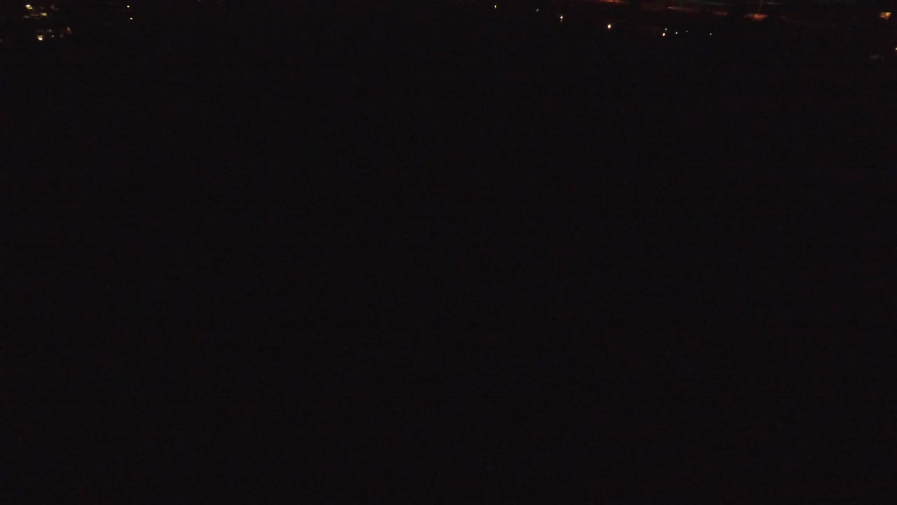 Denver, Colorado at night, seen as a mostly black aerial frame with small warm city lights along the upper edge and no visible people.