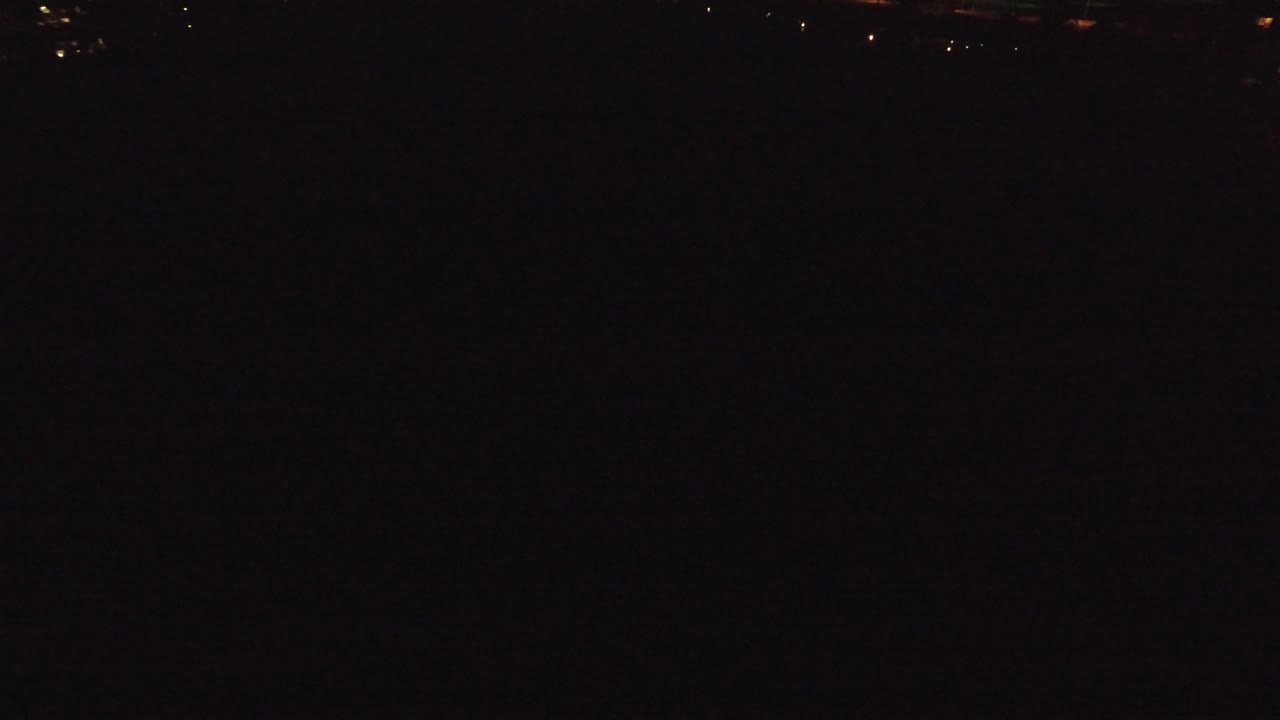 Denver nighttime aerial frame with a narrow line of small orange and white lights across the distant upper area and no visible people.