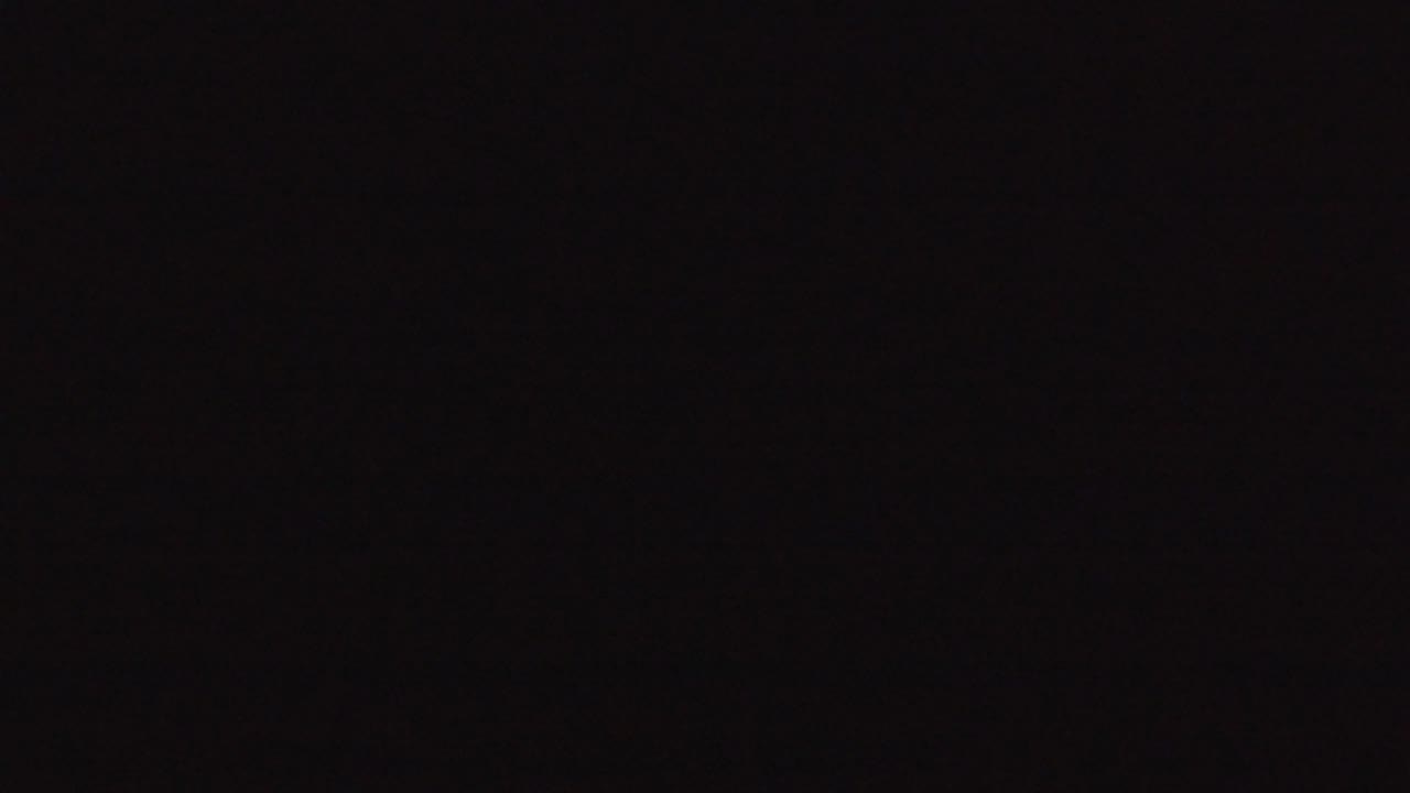 Black frame with subtle low-light grain and shadow.