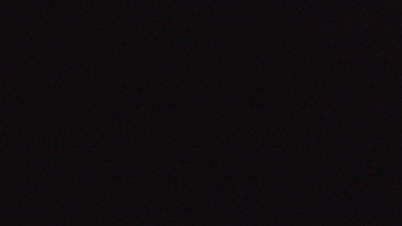 Nearly black frame with faint noise and tiny light specks.