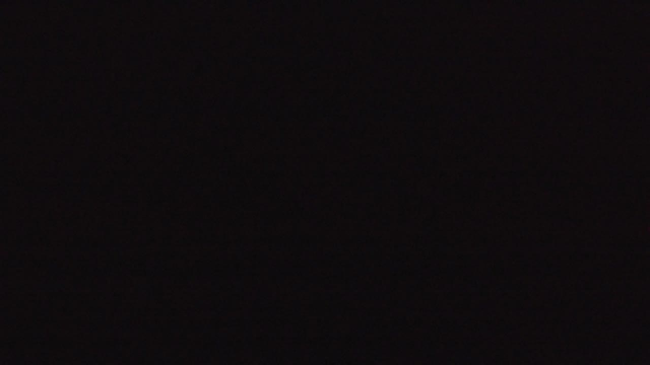 Underexposed Denver 2016 frame dominated by blackness, with a few tiny warm dots and no visible people or readable detail.
