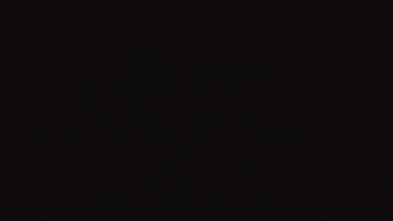 Dark night aerial view with scattered city lights on the horizon.