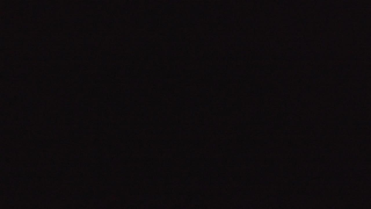 Denver night cityscape frame with small white and warm lights spread across the horizon, deep black sky above, and no visible people.