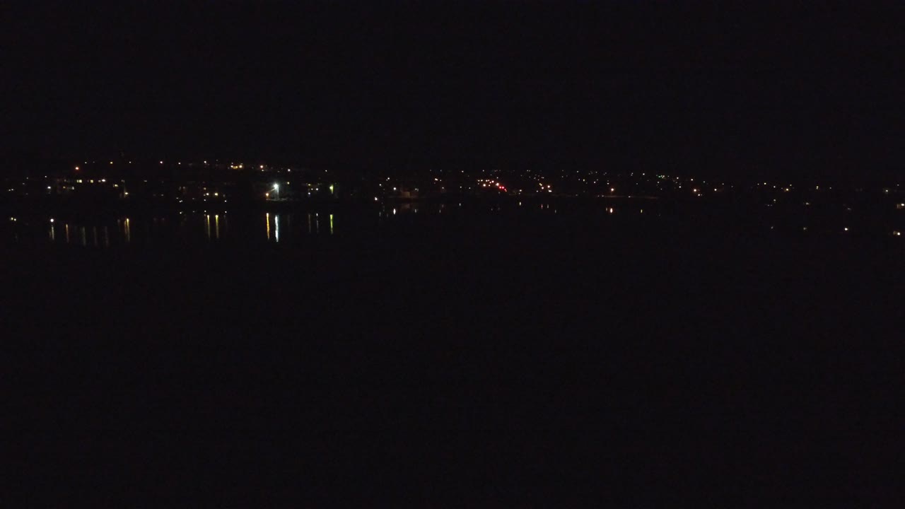Distant city lights reflected on dark water at night