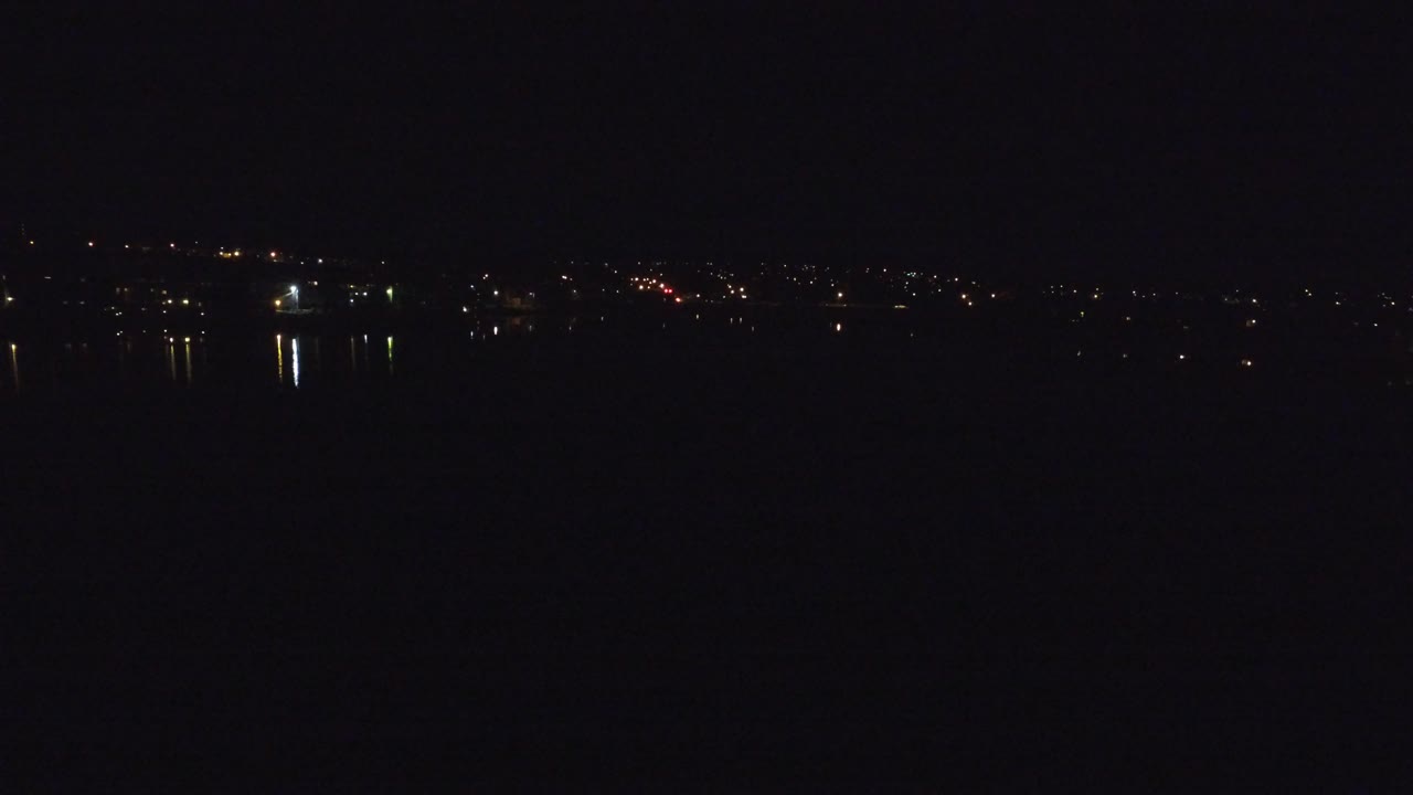 Dark night water with distant shoreline lights and reflections.