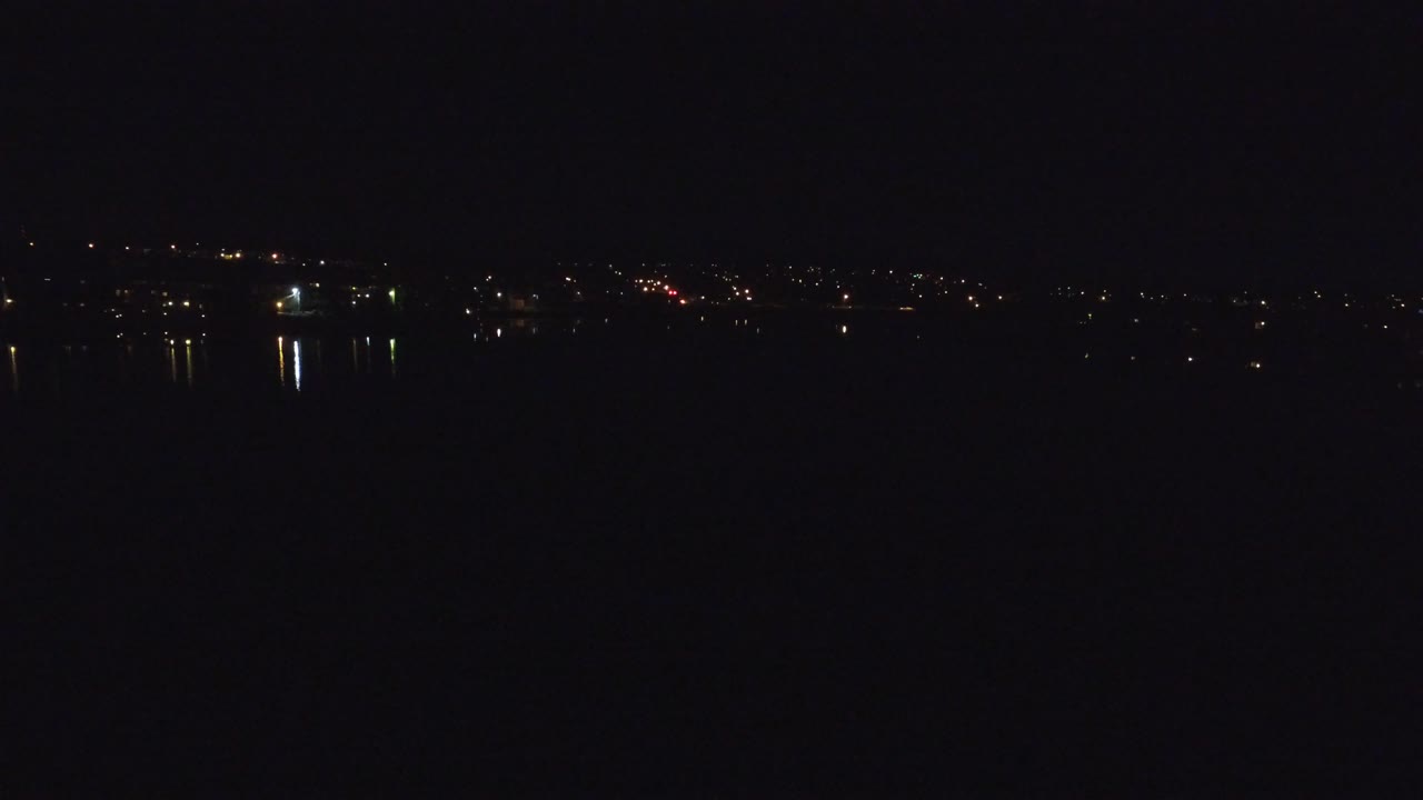 Denver, Colorado night frame with a low horizon, scattered distant lights, brighter white reflections near the left side, and no visible people.