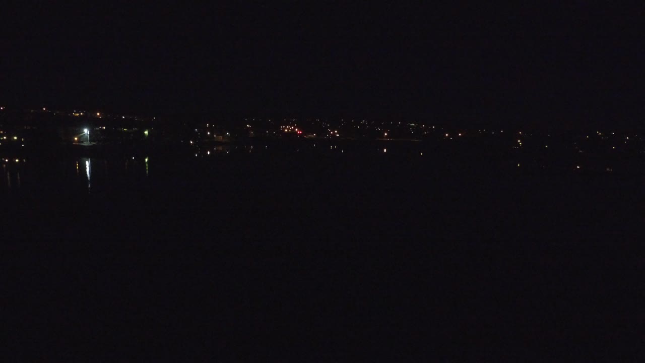 Denver, Colorado at night with a black sky, distant scattered city lights, faint water reflections, and no visible people.