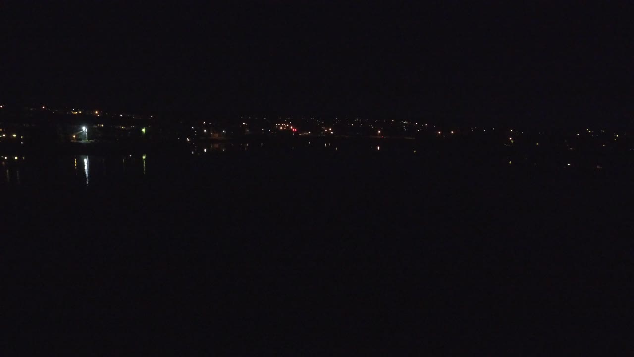 A wide Denver night view holds distant orange and white lights along the horizon with dark water below and no visible people.