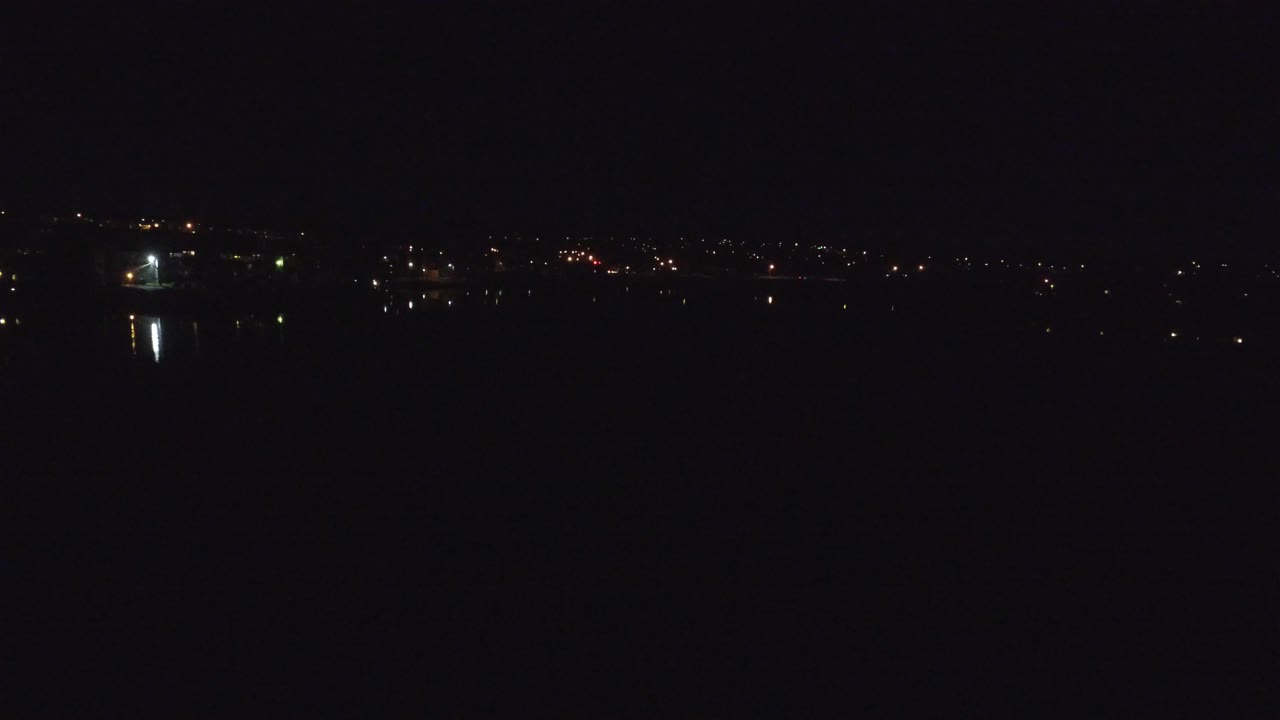 Thin skyline of nighttime city lights under a black sky.