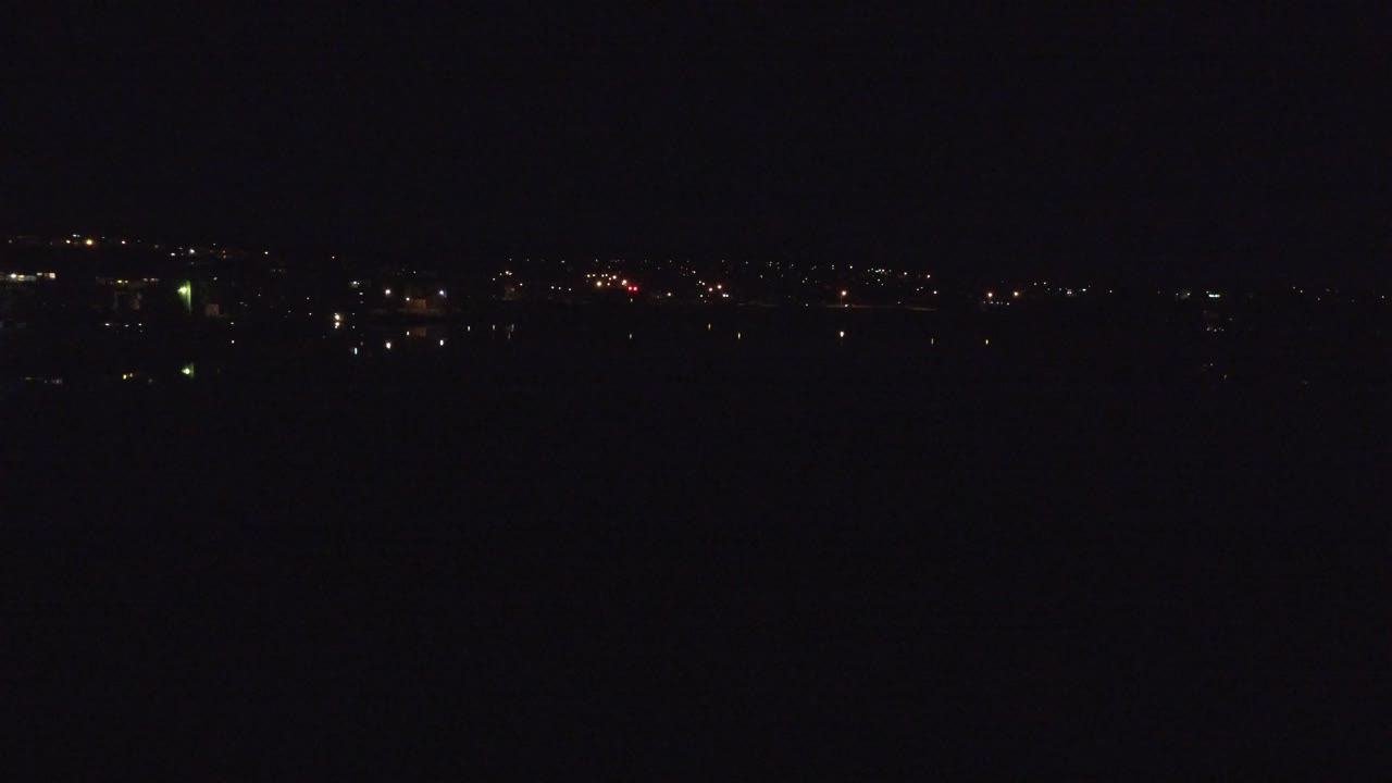 Denver, Colorado nighttime aerial view with sparse city lights along a low horizon, deep black foreground and sky, and no visible people.