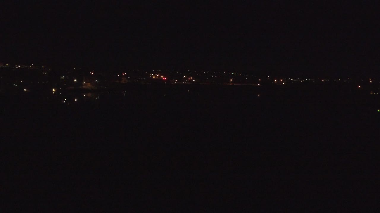 Dark night horizon with scattered distant lights.