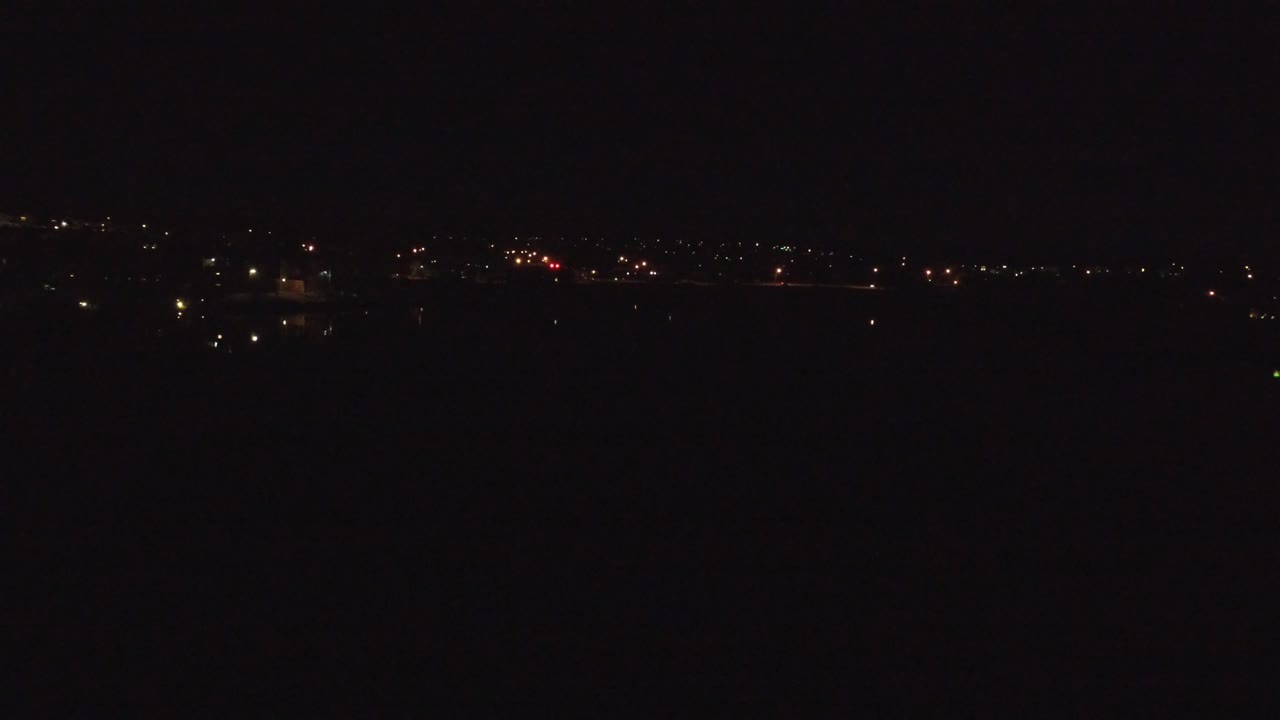 Denver, Colorado night frame with a thin band of distant lights across the upper horizon and deep black foreground, no visible people.