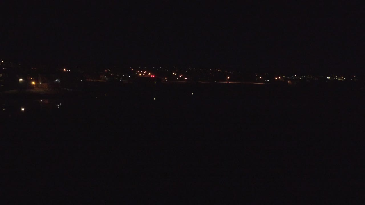 A near-black Denver night frame shows a thin strip of red, orange, and white lights across the upper distance with no visible people.