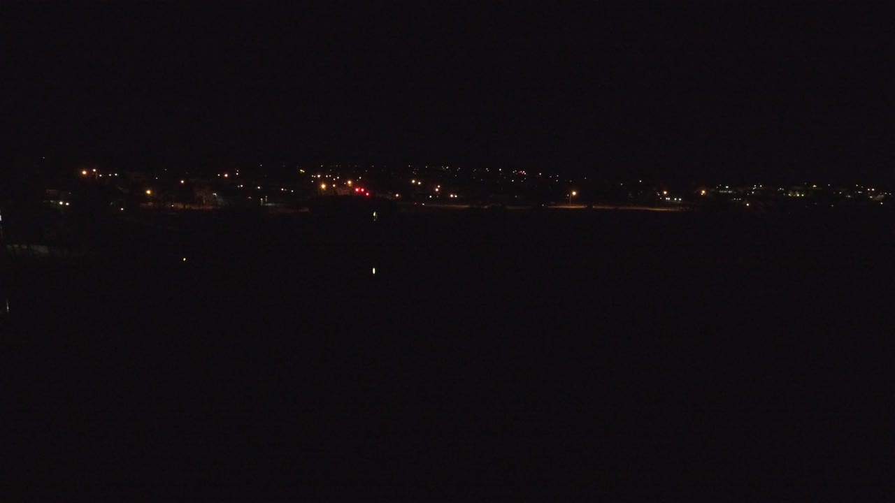 Wide dark Denver night view with a thin strip of distant road and city lights along the horizon, no visible people.