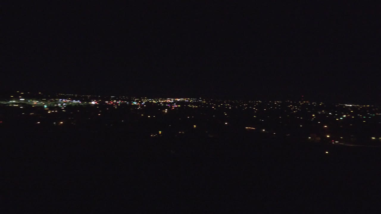 Denver appears as a thin strip of white and yellow lights across the horizon, with a mostly black foreground and no visible people.