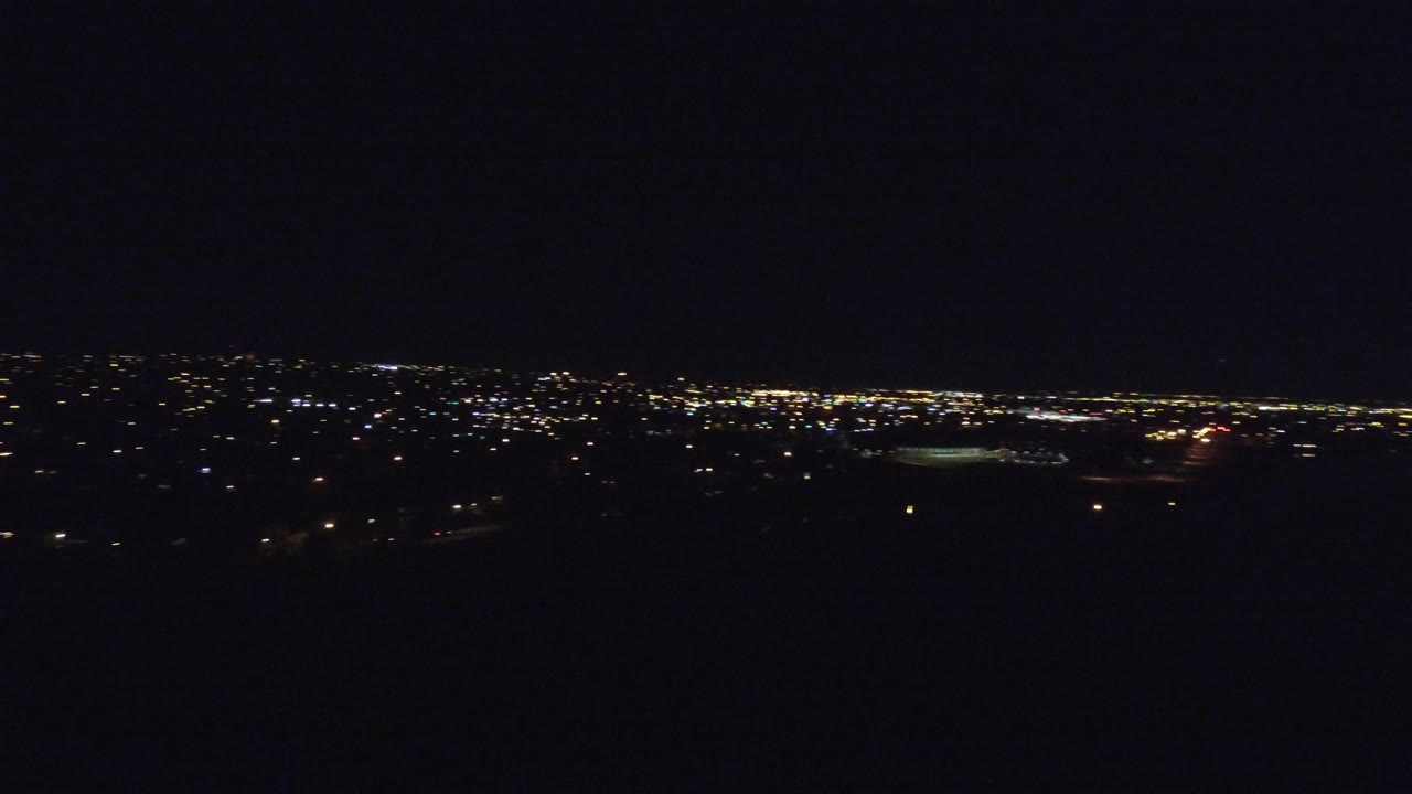 Denver city lights stretch across the middle of the frame at night, with a broad black sky above, deep shadow below, and no visible people.