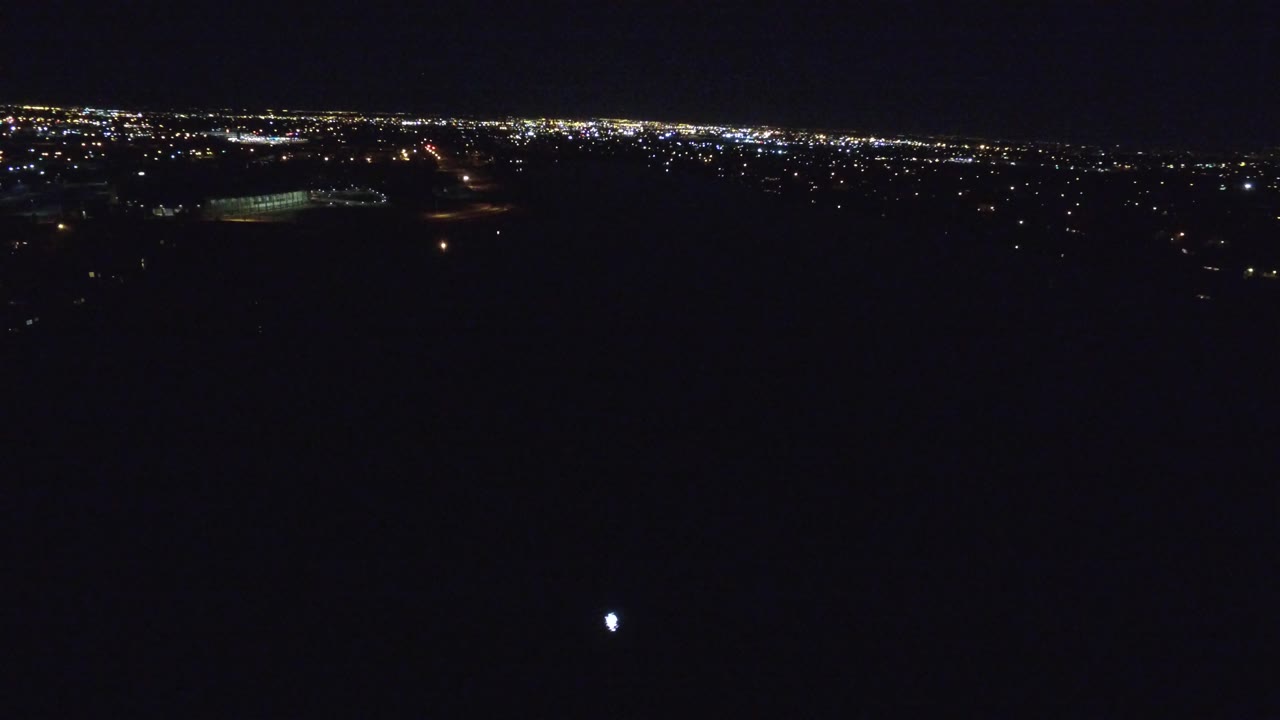 Dark aerial city view with lights stretching across the top of frame