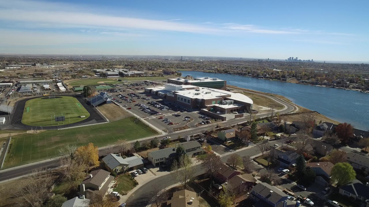 Aerial view of a large complex beside water and athletic fields.