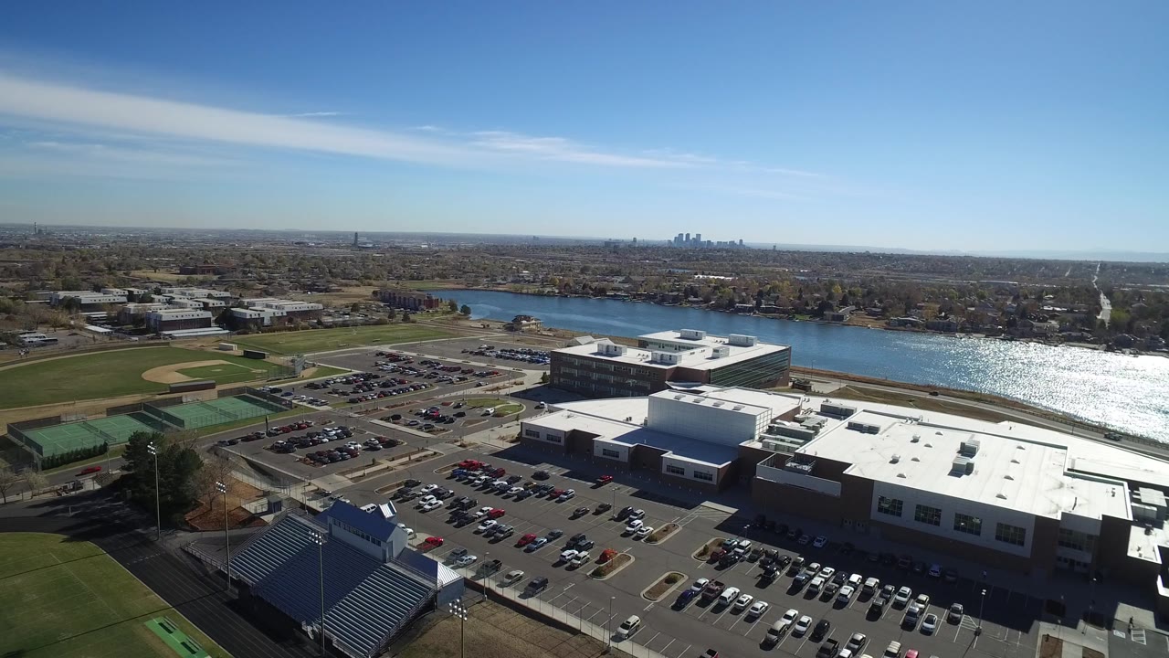 Aerial view of a large building complex, cars, fields, and river glare.
