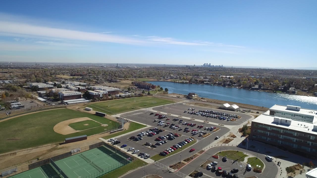 Aerial view of baseball fields, tennis courts, parking lots, campus buildings, and a lake.