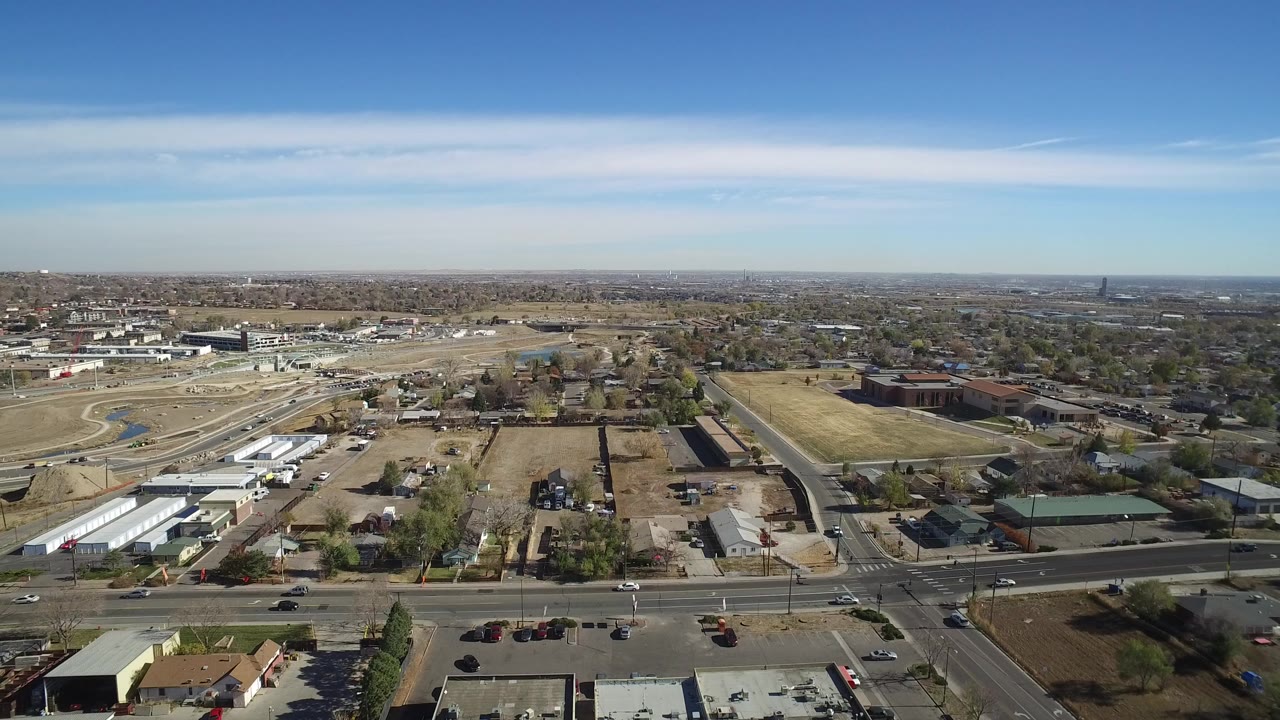 High aerial view of suburban roads, houses, lots, and blue sky.