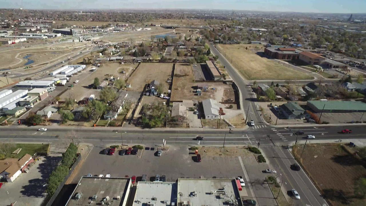 Closer aerial view of a main road, parking areas, homes, and open land.