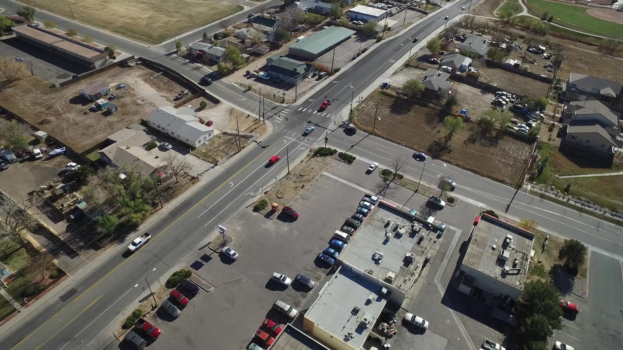 High-angle view of a suburban roadway with cars and building roofs.