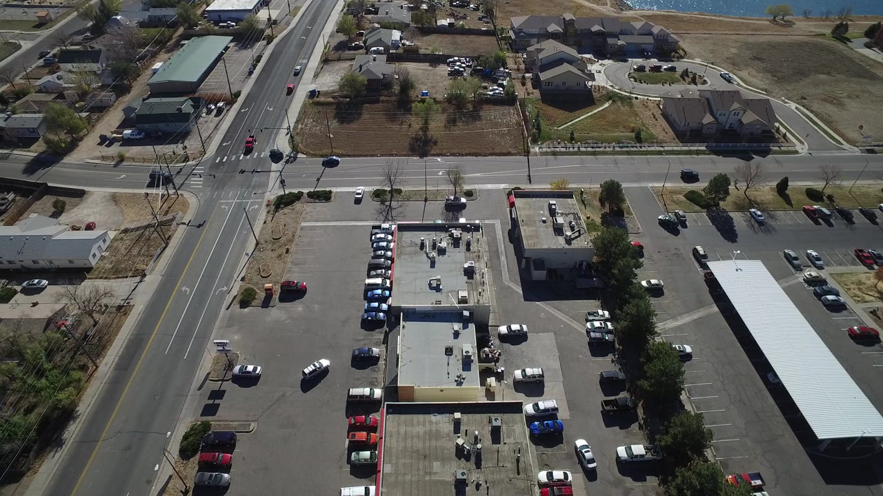 Aerial view of a road intersection, businesses, parking lots, and nearby homes.