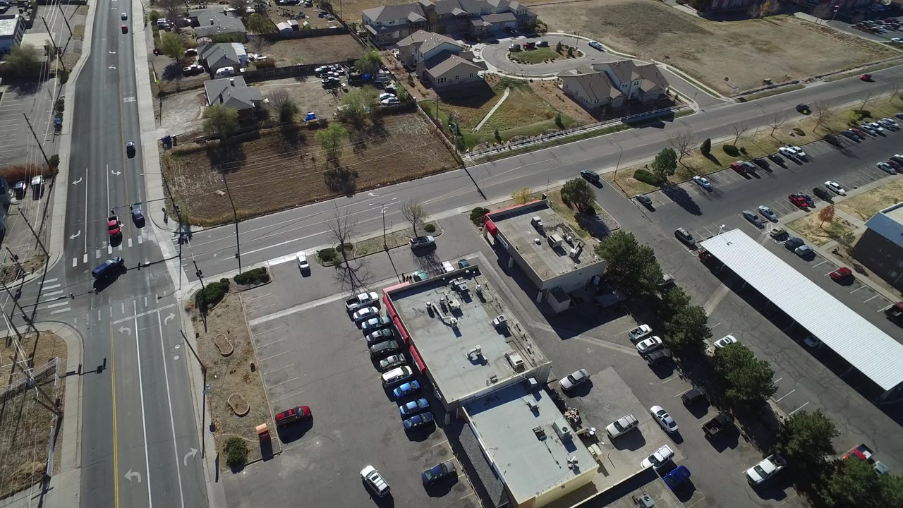 Aerial view of a road intersection beside parking lots and low-rise buildings.