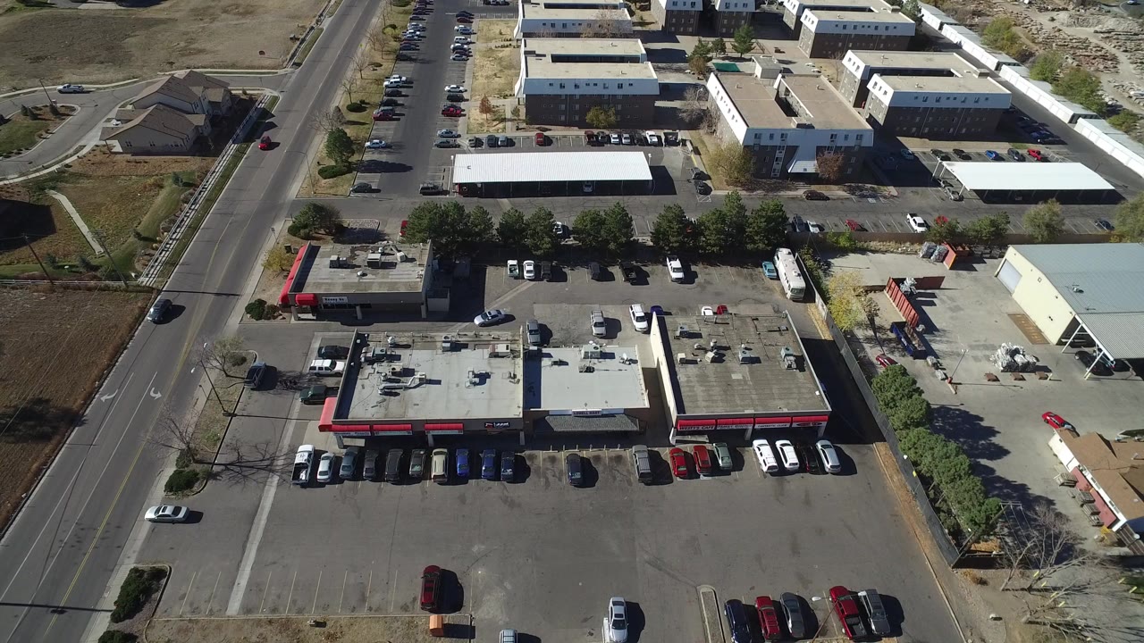 Overhead commercial block with parking lots and a red car on the road.