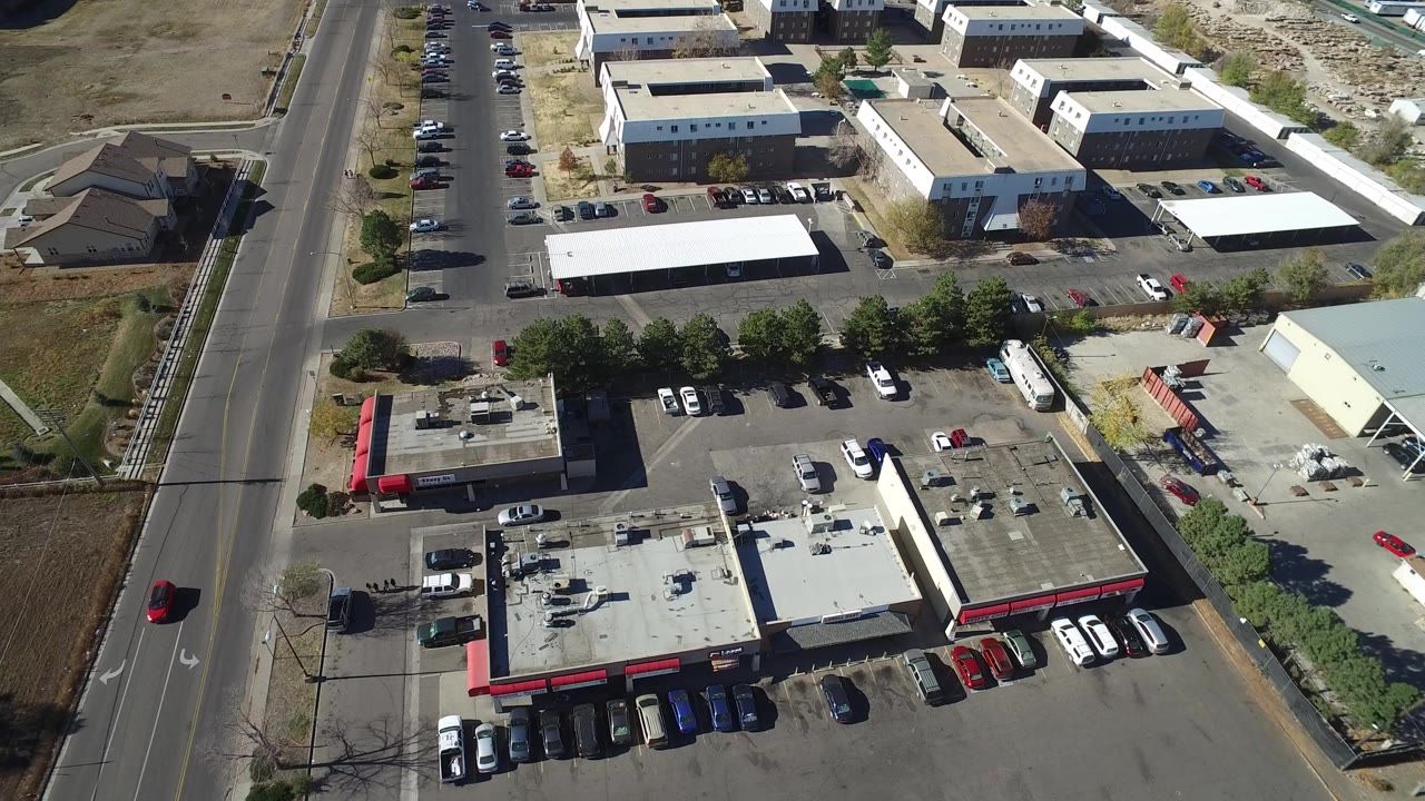 Aerial view of a commercial block, parking lots, cars, and a road.