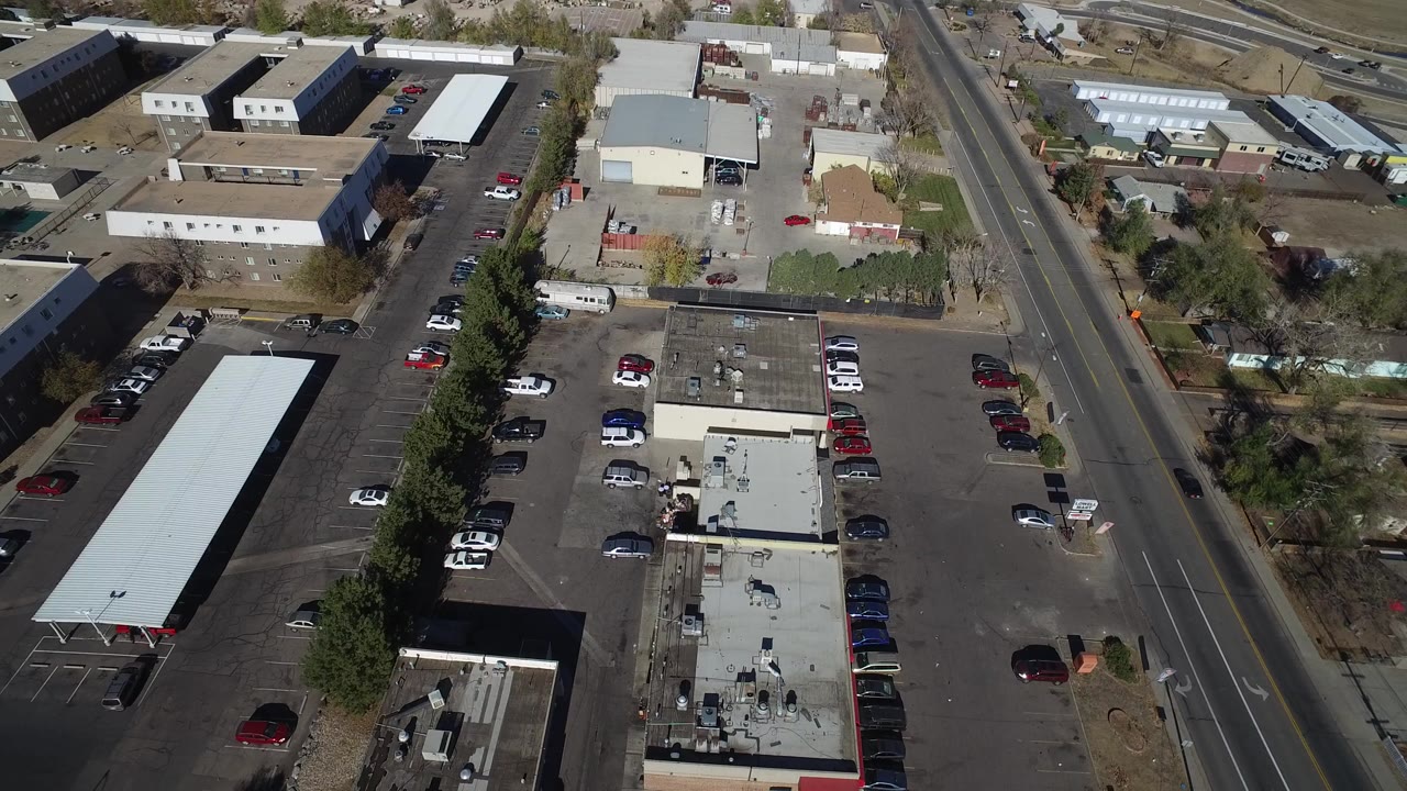 Aerial view of parking lots, low buildings, cars, and a road.