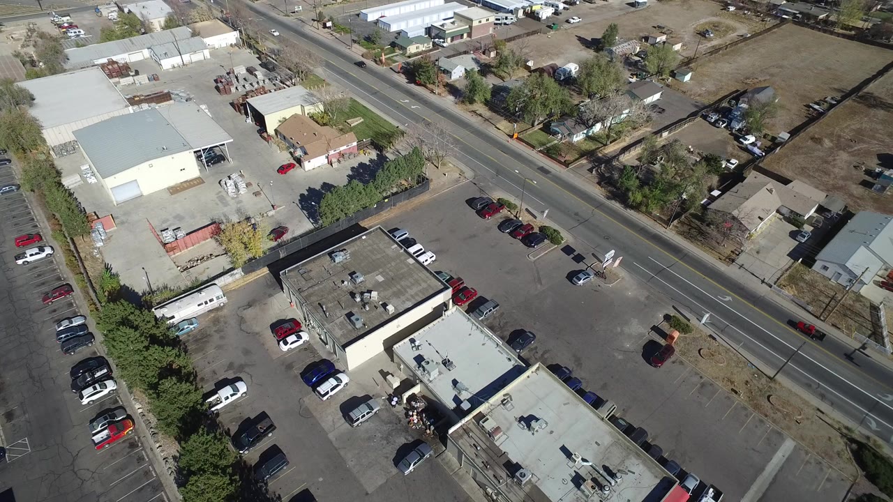 Overhead view of parking lots, low buildings, parked cars, and a diagonal road.