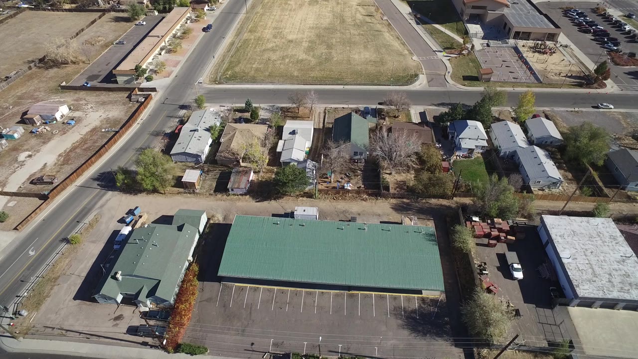 At 0:01, the Westminster, Colorado aerial view keeps the long green roof centered below homes and intersecting streets, with no visible people in the bright daylight scene.