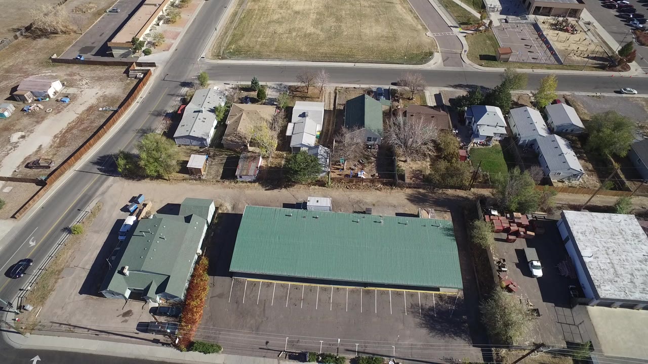 Aerial view of roads, homes, lawns, and green-roofed buildings.