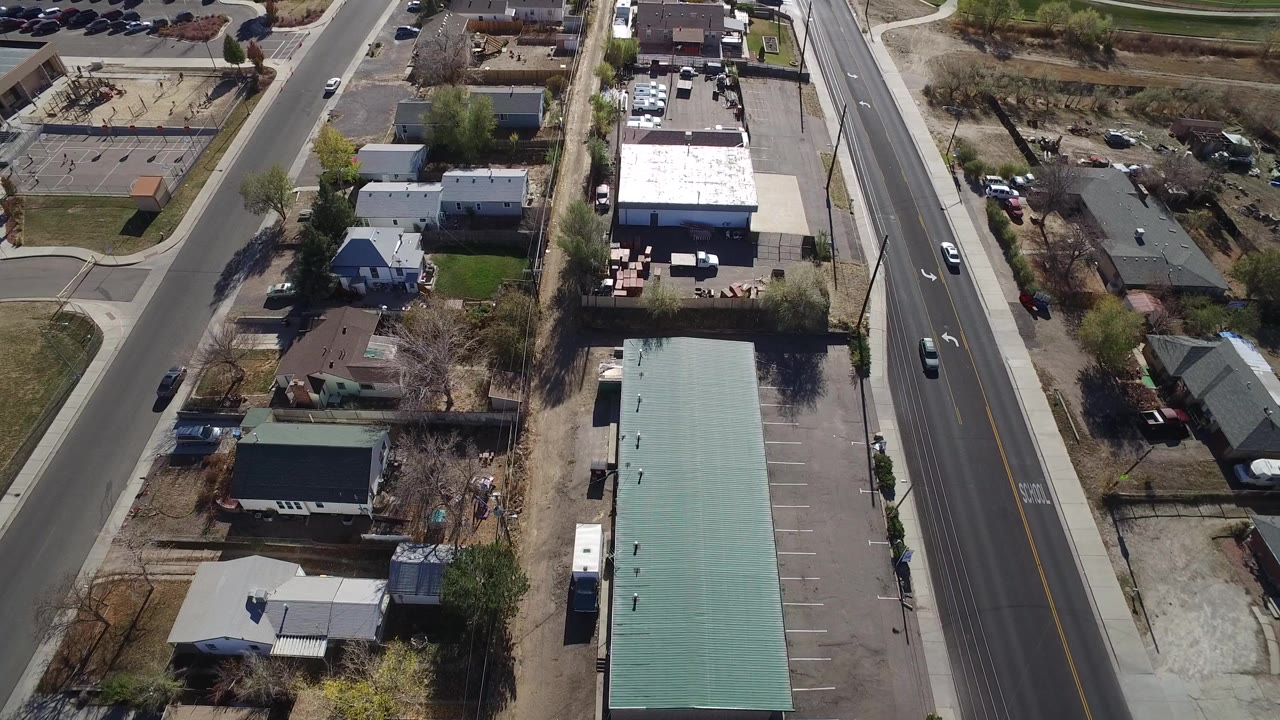Aerial view of a road beside houses and low commercial buildings.