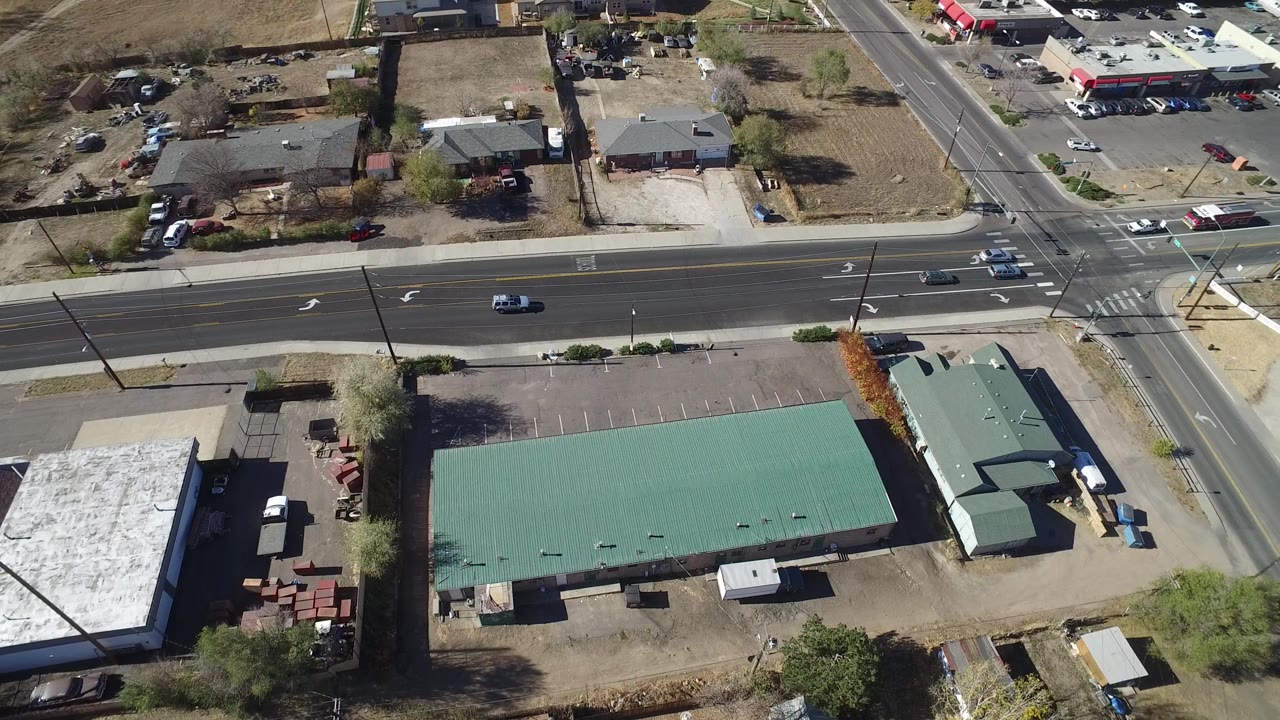 Drone view of a suburban commercial building, parking lot, and cross street.