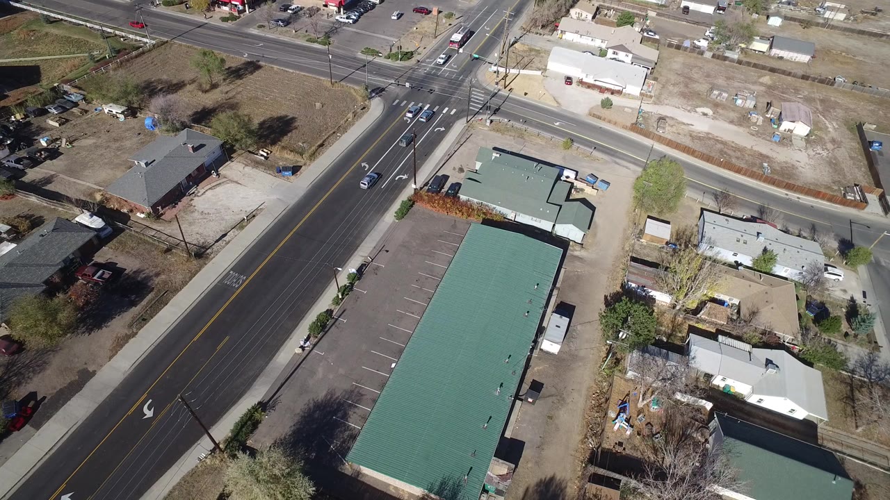Aerial view of a road intersection beside a green-roofed commercial building.