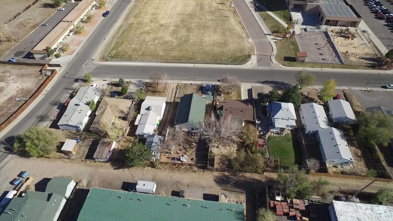 Aerial view of houses, a road, and a large dry grass field.