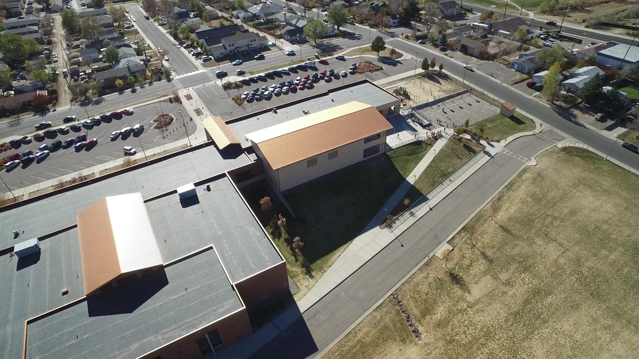 Aerial view of buildings, parking lot, streets, and dry grass.