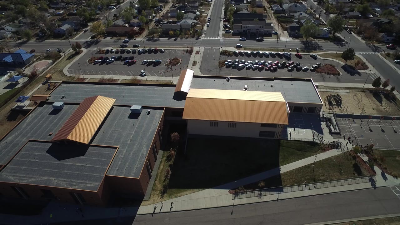 Aerial view of modern buildings, parking lot, road, and houses.