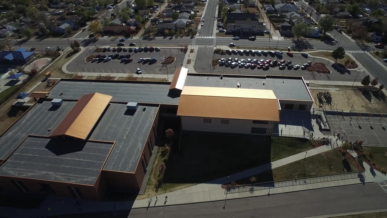 Aerial frame in Westminster, Colorado showing the building roofs shifted slightly in view, with parked cars, streets, houses, and no visible people.