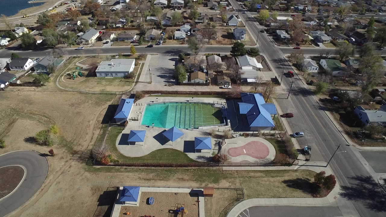 Aerial view of an outdoor swimming pool complex beside residential streets.