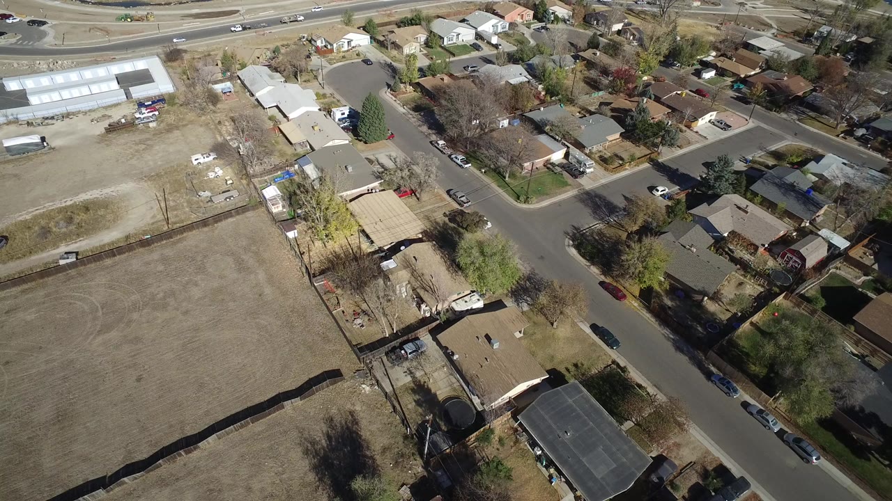 Aerial view of suburban houses beside a dry open field and roads.