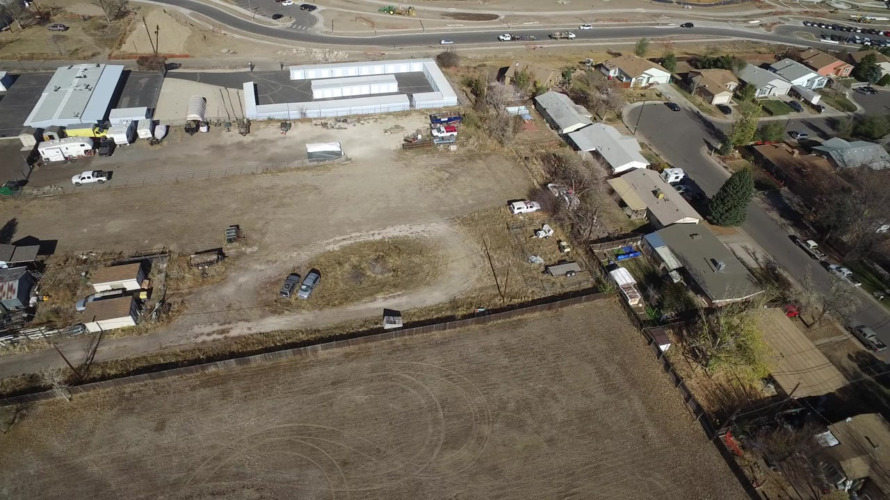 Aerial view of dry lots, houses, sheds, parked vehicles, and a road