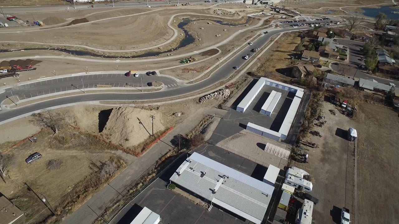 Aerial view of curved roads, open lots, buildings, and a small stream.