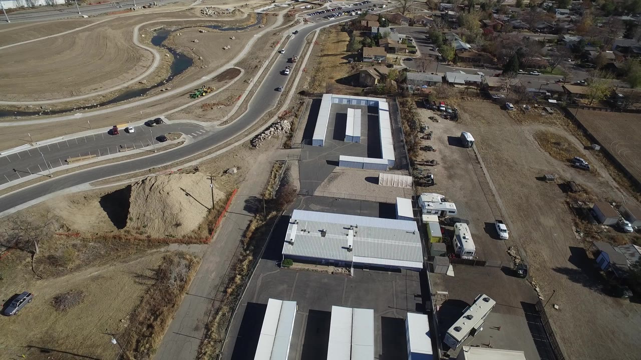 Aerial view of commercial buildings beside a curving roadway and graded land.