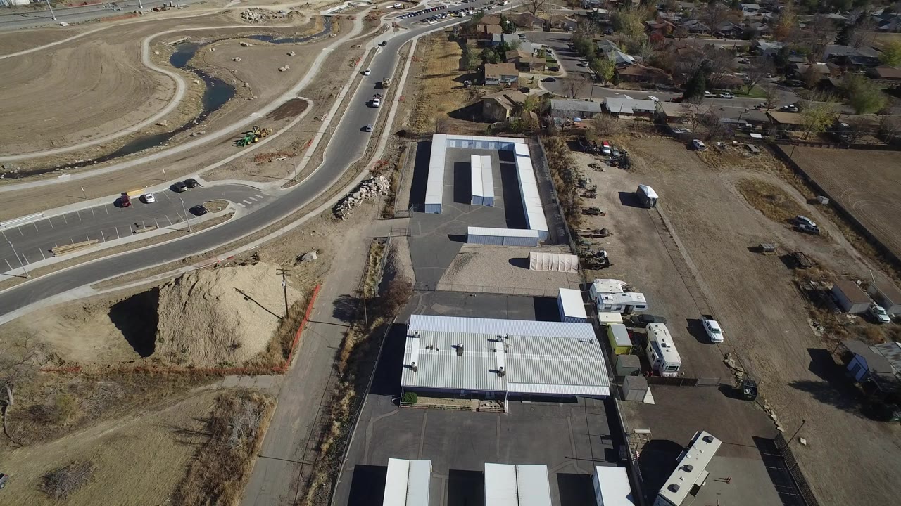Aerial shot of commercial roofs, storage trailers, road lanes, and open land.
