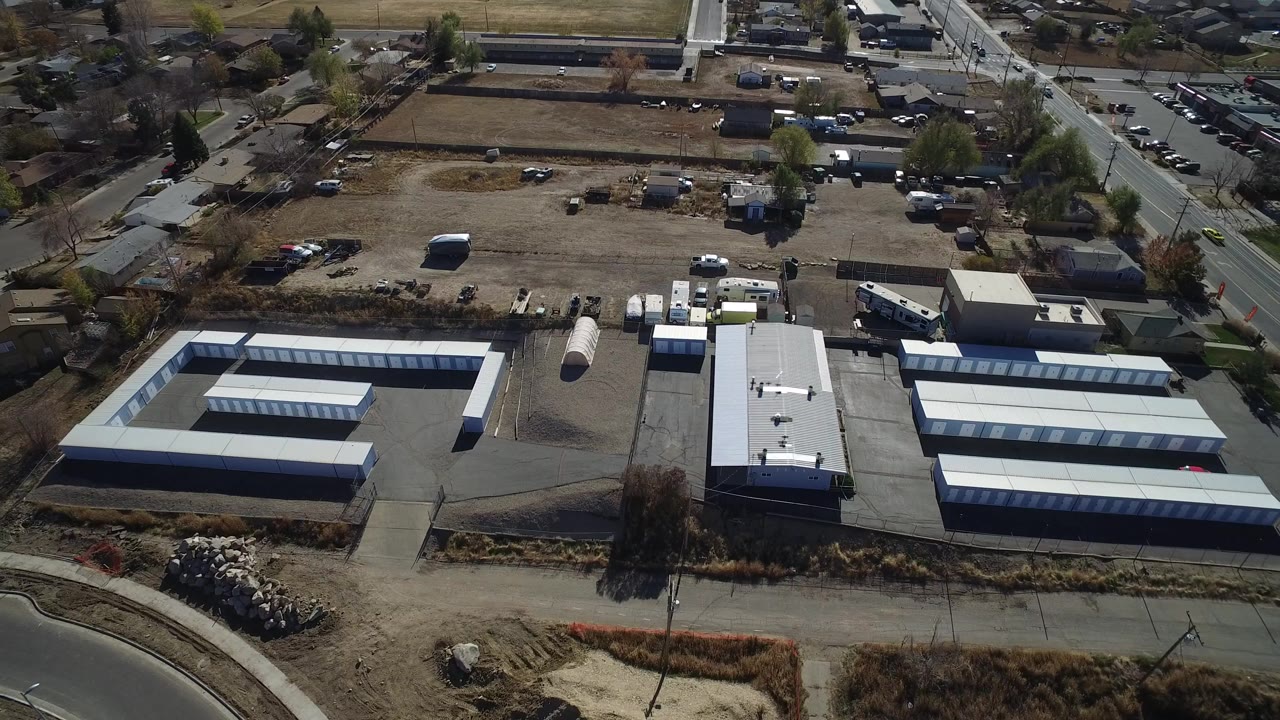 Aerial view of white-roofed industrial buildings beside roads and dirt lots.