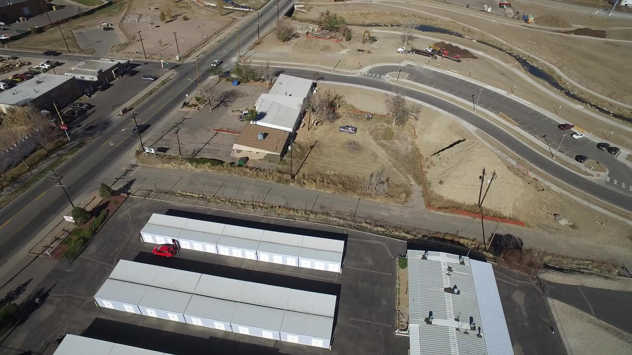 Aerial view of roads, dry lots, low buildings, and white storage units.